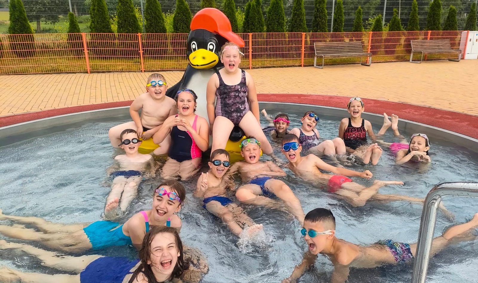 Roześmiane dzieci na zajęciach letnich Aquademy Lubin na otwartym basenie